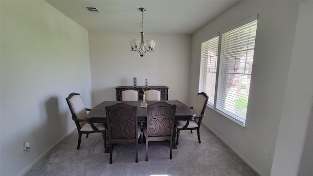 dining area featuring light carpet, a wealth of natural light, and a chandelier