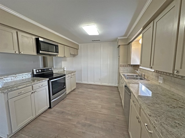 kitchen featuring sink, light stone countertops, ornamental molding, stainless steel appliances, and a textured ceiling