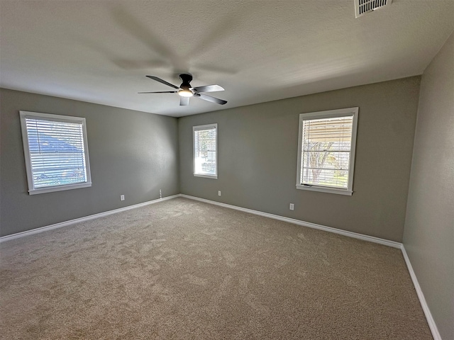 spare room with ceiling fan, a wealth of natural light, and carpet flooring