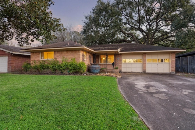 ranch-style house with a garage and a yard