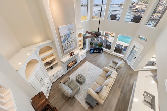 living room featuring dark wood-type flooring, a water view, a towering ceiling, and ceiling fan