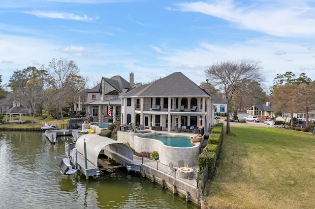 back of house featuring a patio, a balcony, a water view, and a lawn