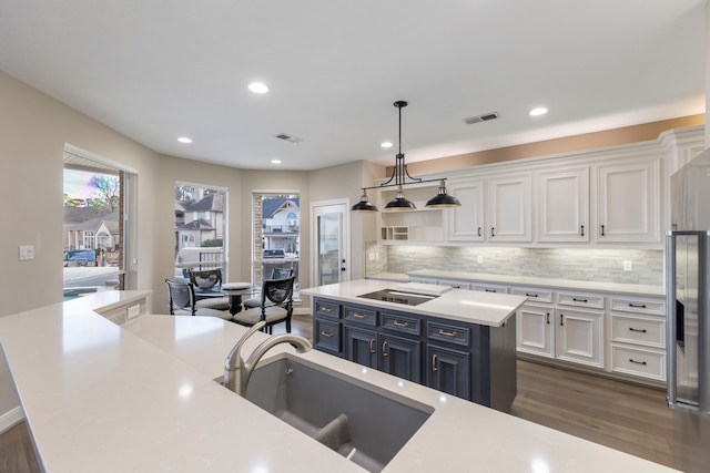 kitchen featuring a spacious island, pendant lighting, white cabinets, tasteful backsplash, and sink