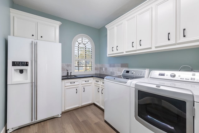 washroom with sink, cabinets, washing machine and dryer, and light wood-type flooring