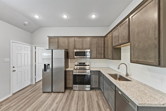 kitchen featuring appliances with stainless steel finishes, tasteful backsplash, sink, light wood-type flooring, and light stone counters