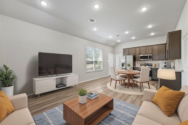 living room with vaulted ceiling, sink, and hardwood / wood-style floors