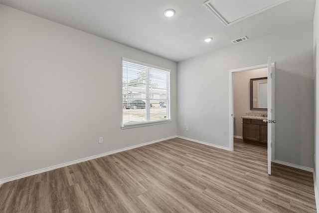 unfurnished bedroom with light wood-type flooring and ensuite bath