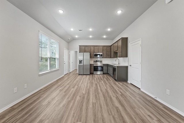 kitchen featuring appliances with stainless steel finishes, light hardwood / wood-style floors, sink, vaulted ceiling, and dark brown cabinets