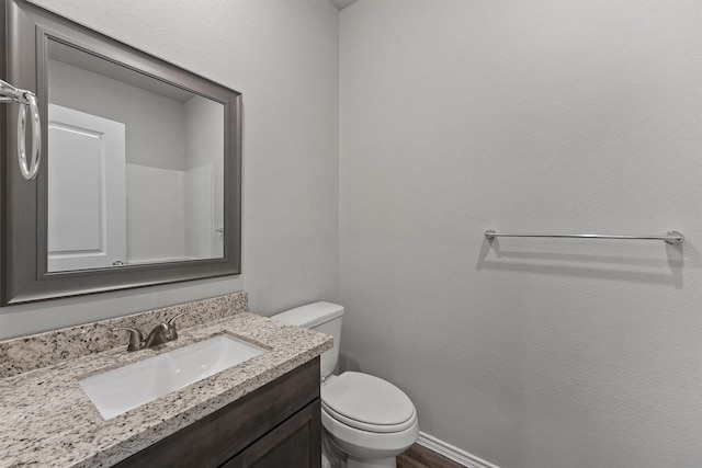 bathroom with toilet, hardwood / wood-style floors, and vanity