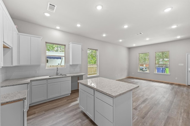 kitchen featuring a kitchen island, decorative backsplash, light hardwood / wood-style floors, and sink