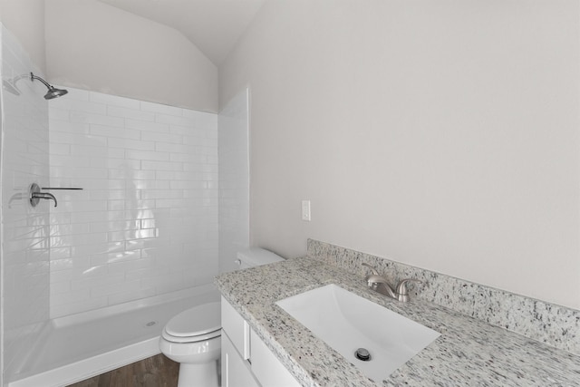 bathroom with lofted ceiling, vanity, toilet, hardwood / wood-style flooring, and tiled shower