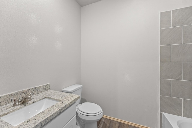 bathroom featuring toilet, a bathing tub, wood-type flooring, and vanity