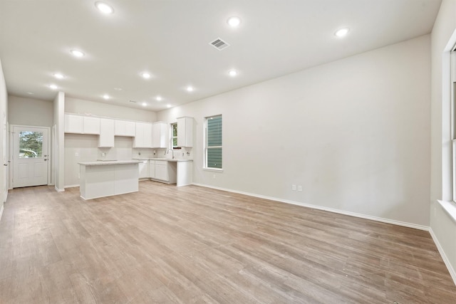 unfurnished living room with sink and light hardwood / wood-style flooring