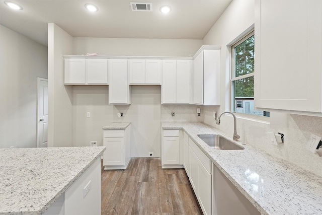 kitchen featuring light stone countertops, sink, and white cabinetry