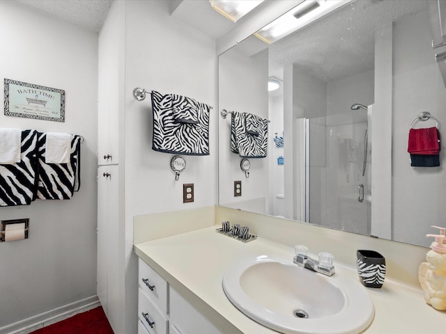 bathroom with walk in shower, vanity, and a textured ceiling