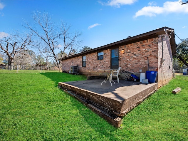 rear view of house with central AC unit, a lawn, and a patio