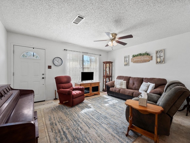 living room with a textured ceiling, tile patterned floors, and ceiling fan