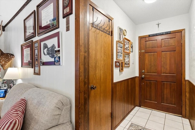 corridor with a textured ceiling, wood walls, and light tile patterned flooring