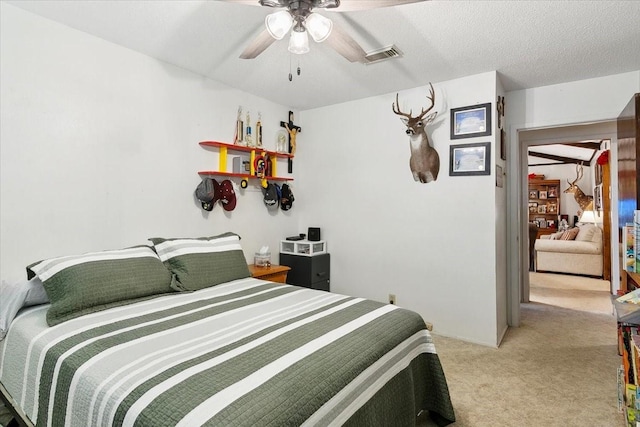 bedroom featuring ceiling fan, light colored carpet, and a textured ceiling