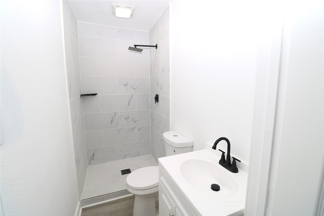 bathroom with hardwood / wood-style floors, toilet, vanity, and tiled shower