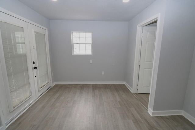 spare room with french doors and light hardwood / wood-style flooring