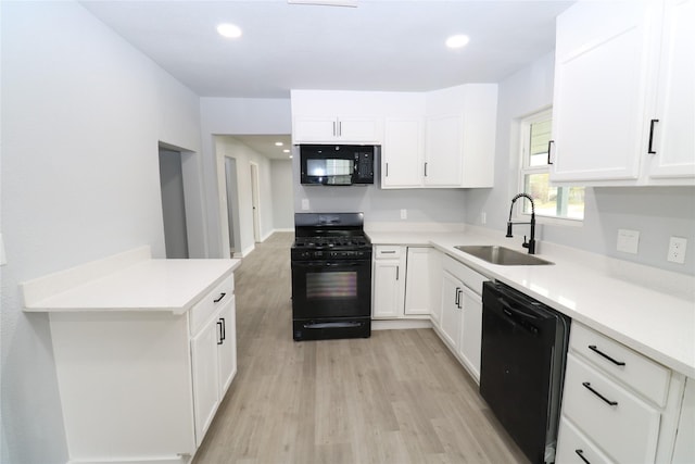 kitchen featuring sink, white cabinets, black appliances, and light wood-type flooring