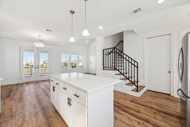 kitchen with hanging light fixtures, a center island, white cabinets, and stainless steel refrigerator