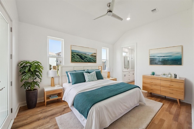 bedroom with ceiling fan, ensuite bath, vaulted ceiling, and light wood-type flooring