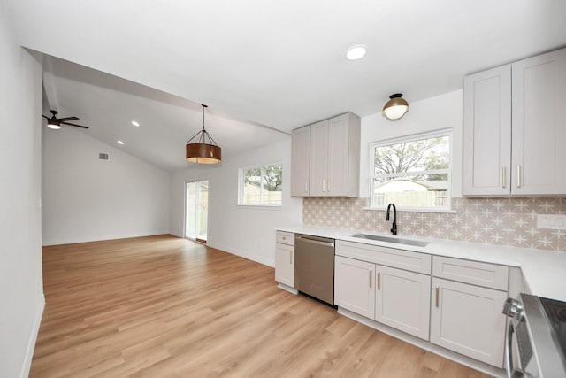 kitchen with pendant lighting, lofted ceiling, stainless steel appliances, tasteful backsplash, and sink