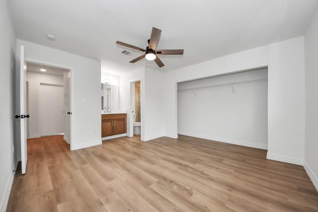 unfurnished bedroom featuring ceiling fan, a closet, ensuite bath, and light hardwood / wood-style flooring