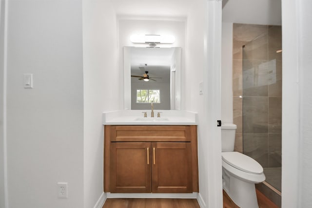 bathroom featuring hardwood / wood-style floors, a shower with door, vanity, toilet, and ceiling fan