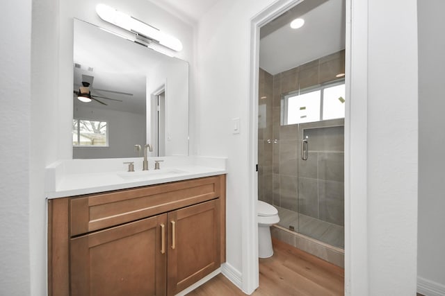 bathroom featuring toilet, ceiling fan, wood-type flooring, walk in shower, and vanity