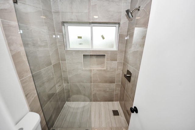 bathroom featuring toilet and a tile shower