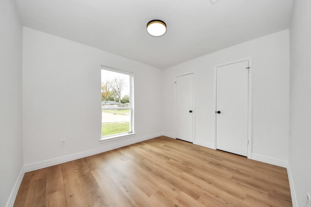 unfurnished bedroom featuring two closets and light hardwood / wood-style flooring