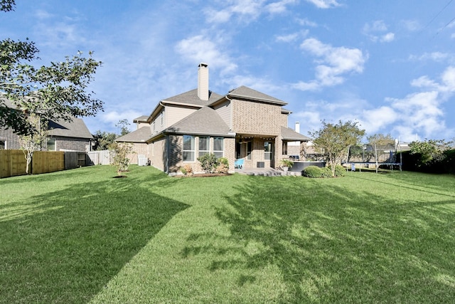 back of house with a yard and a trampoline