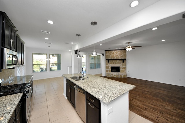 kitchen with appliances with stainless steel finishes, a kitchen island with sink, sink, decorative light fixtures, and ceiling fan