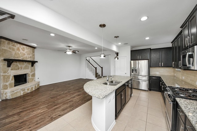 kitchen with sink, stainless steel appliances, a center island with sink, and light tile patterned floors