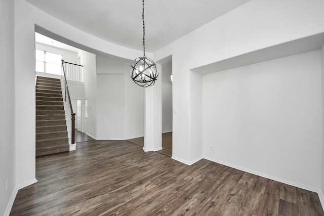 unfurnished dining area with a notable chandelier and dark hardwood / wood-style floors