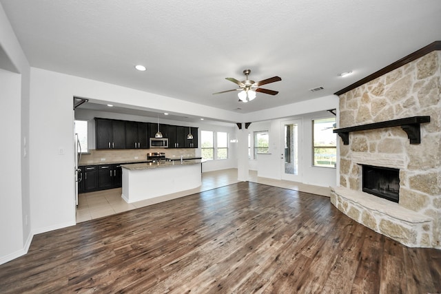 unfurnished living room featuring light wood-type flooring, ceiling fan, and a fireplace