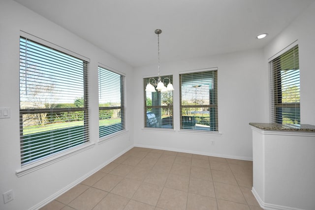 unfurnished dining area featuring a wealth of natural light, light tile patterned floors, and a chandelier