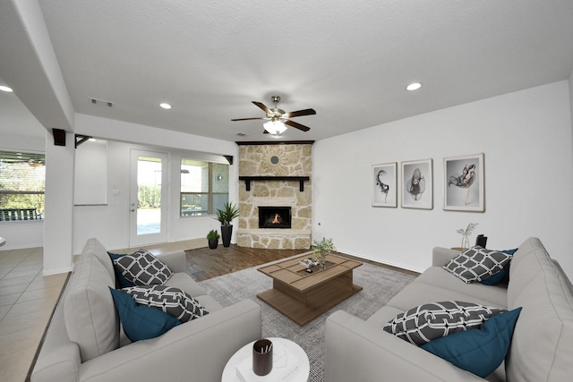 living room featuring a fireplace, tile patterned flooring, ceiling fan, and a healthy amount of sunlight