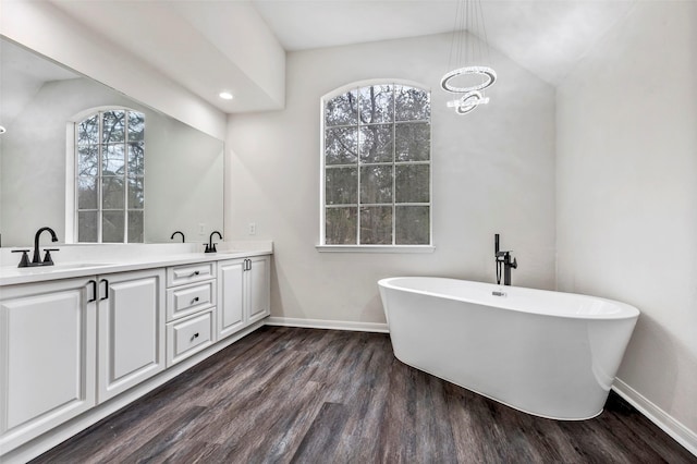 bathroom with lofted ceiling, a bathtub, hardwood / wood-style floors, and vanity