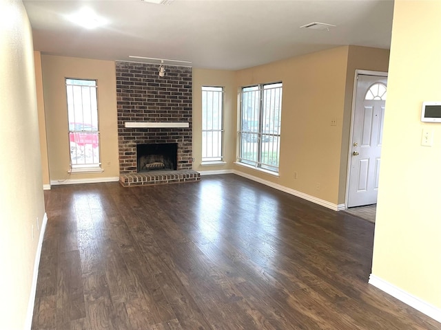 unfurnished living room featuring dark wood-type flooring and a brick fireplace