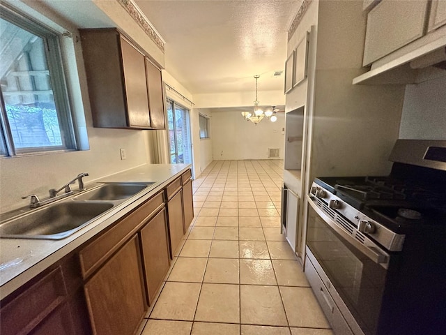 kitchen featuring a notable chandelier, sink, stainless steel range with gas stovetop, light tile patterned flooring, and hanging light fixtures