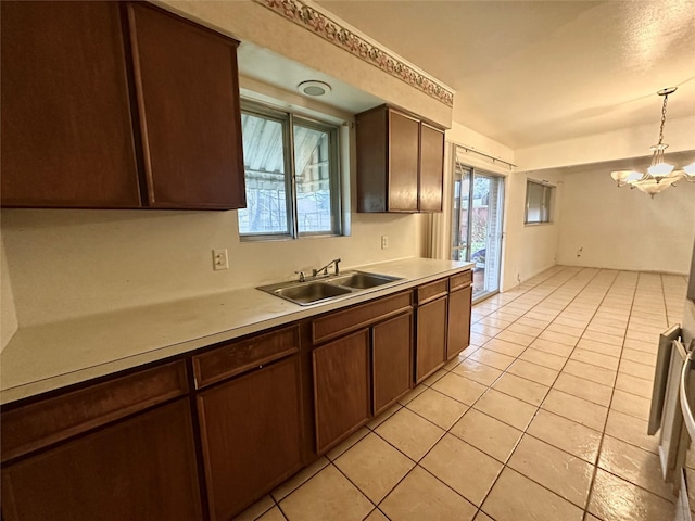 kitchen with light tile patterned floors, a notable chandelier, pendant lighting, dark brown cabinetry, and sink