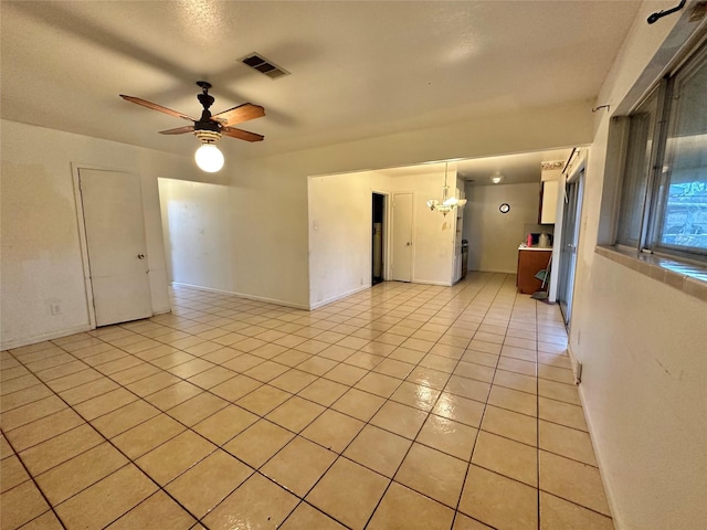 unfurnished room with light tile patterned floors and ceiling fan with notable chandelier