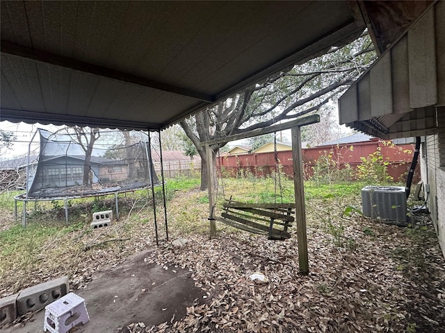 view of yard with a trampoline, central AC, and a patio