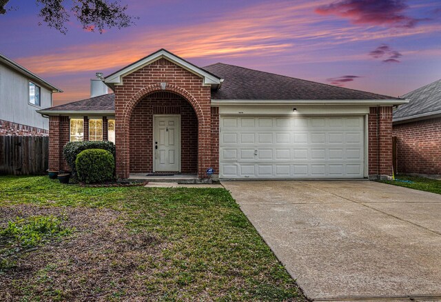 single story home featuring a garage and a yard