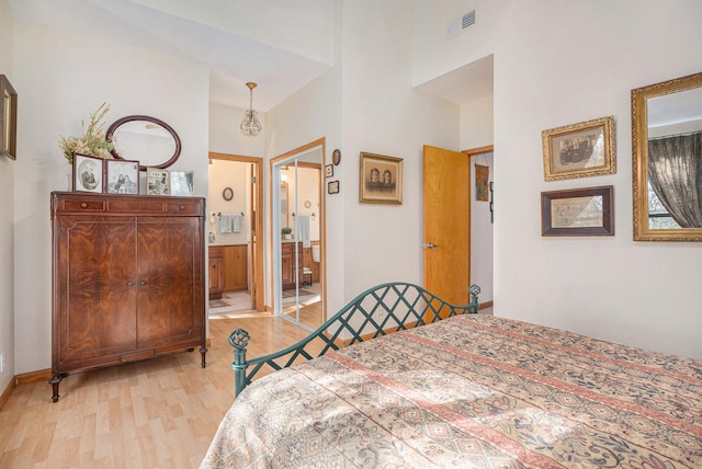 bedroom featuring ensuite bath, a high ceiling, and light hardwood / wood-style floors