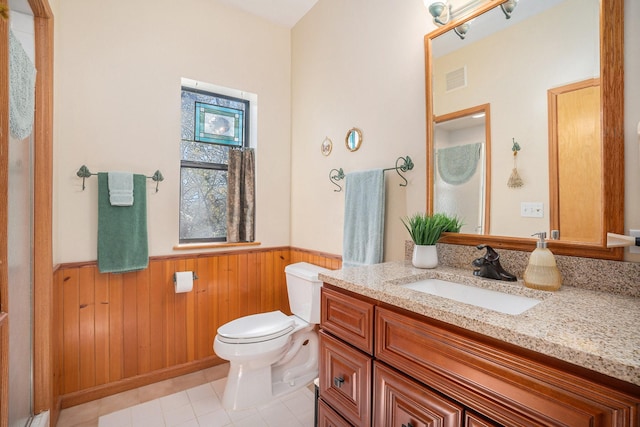 bathroom with toilet, vanity, tile patterned flooring, and wooden walls